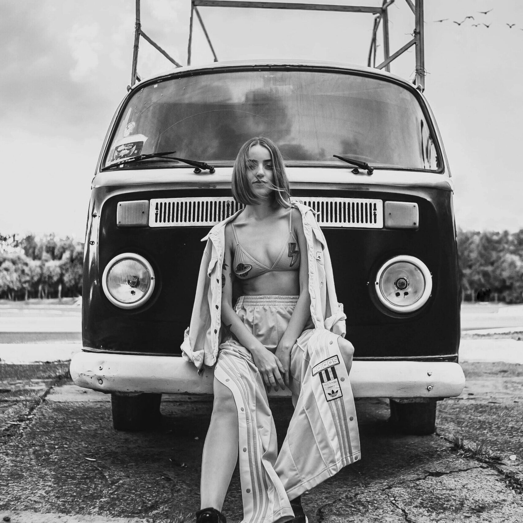 Stylish woman poses in front of a classic Volkswagen van. Black and white photography.